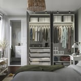 Modern bedroom with open wardrobe displaying clothes, drawers, and storage; integrated lighting and adjustable shelves.