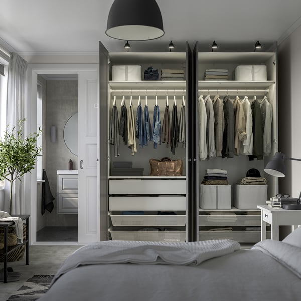 Modern bedroom with organized open wardrobe. Clothes hung neatly, drawers below, integrated lighting.