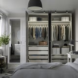 Modern bedroom with organized open wardrobe. Clothes hung neatly, drawers below, integrated lighting.
