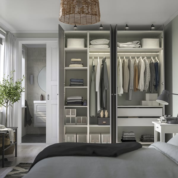 Bedroom with organized wardrobe featuring shelves, hanging space, and under-lit drawers. A door leads to a bathroom.