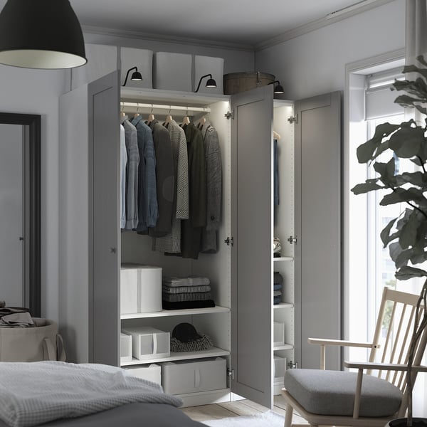 Open wardrobe with clothes, shelves, boxes, and light.