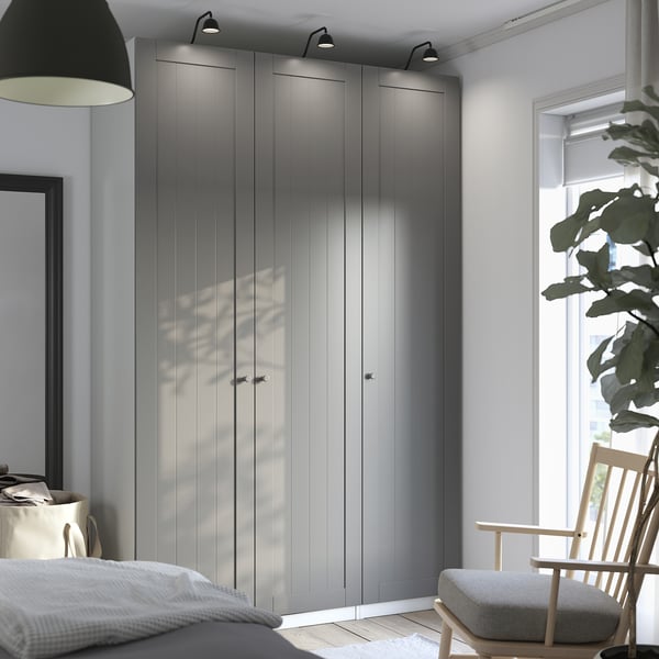 Modern bedroom: large PAX wardrobes with lights between. Wooden rocking chair by window.