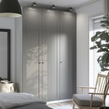Modern bedroom: large PAX wardrobes with lights between. Wooden rocking chair by window.