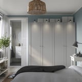 Bedroom with large PAX wardrobe, soft-close hinges, pendant light, and bathroom view with bathtub and mirror. Large bed with folded blankets.