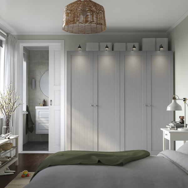 Minimalist bedroom: large grey PAX wardrobe, white lamp, green bed cover, white side tables.