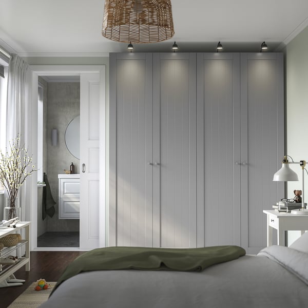 Modern bedroom with gray PAX wardrobe, integrated lights, en suite bathroom, and comfy bed with green and gray bedding.