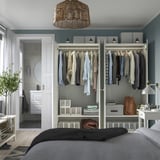 Neat bedroom with grey walls, white PAX wardrobes, and organized clothes. Light fixture, bathroom access.
