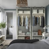 Modern bedroom with open wardrobe displaying neatly organized clothes, featuring adjustable shelves and integrated lighting.