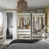 A modern bedroom a PAX wardrobe with mesh drawers for clothes, adjustable shelving, and integrated lighting.