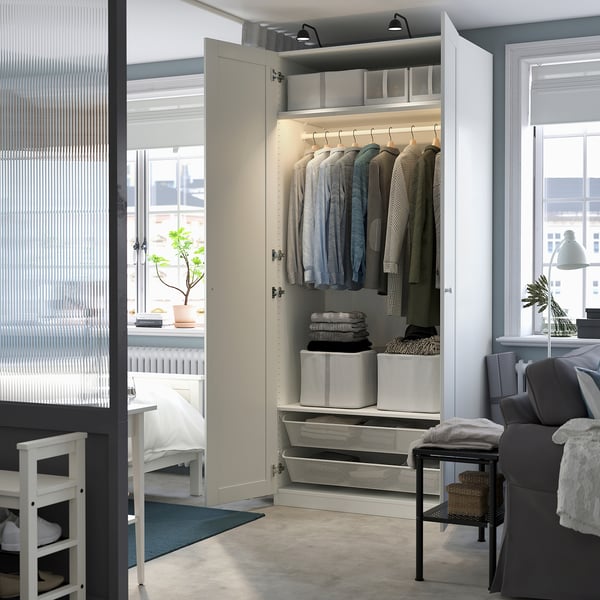 Open wardrobe with clothes, organized shelves, and storage boxes. Integrated lighting illuminates the closet space.