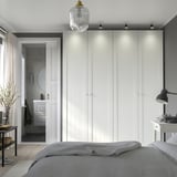Modern bedroom: large white PAX wardrobe with integrated lighting, gray bed, and gray bathroom through doorway.