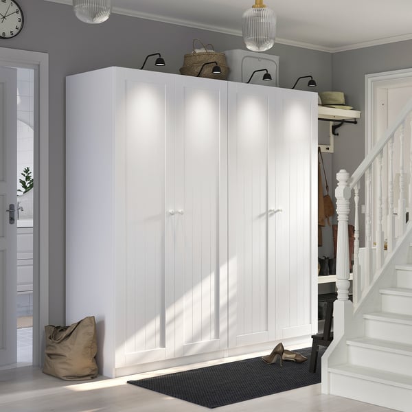 PAX white wardrobe, modern, large, fits entryway, includes shelves and hooks, with stairs nearby.