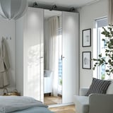 Modern white wardrobe with mirrored doors and urban view.