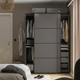 Modern wardrobe with hanging clothes, drawers, and adjustable shelves in a bedroom setting.