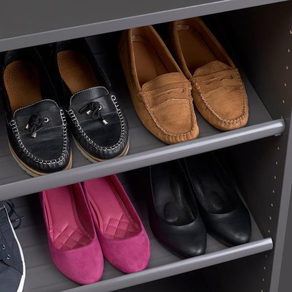 Well-organized shoe rack with 4 pairs of stylish, clean, and neatly arranged mens shoes on two shelves.