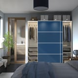 Modern bedroom with blue wardrobe featuring sliding doors, hanging clothes, and shelves.