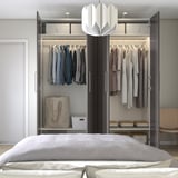 Modern bedroom with open wardrobe: clothes on hangers, shelves, and bags on floor. Soft closing doors, adjustable feet.