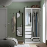 Modern bedroom with open PAX wardrobe displaying clothes, shelves, and drawers. Mirror and lighting included.