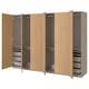 Wooden PAX wardrobe, light brown, modular design with open doors revealing adjustable shelves, drawers, and hanging space.