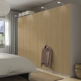 Modern bedroom with light wood PAX wardrobe and wall lamps.