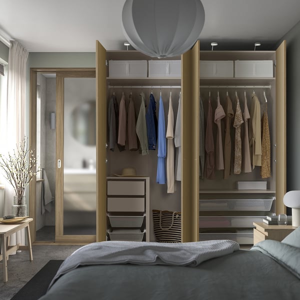 Modern bedroom with gray bed and open PAX wardrobe, showing organized storage.