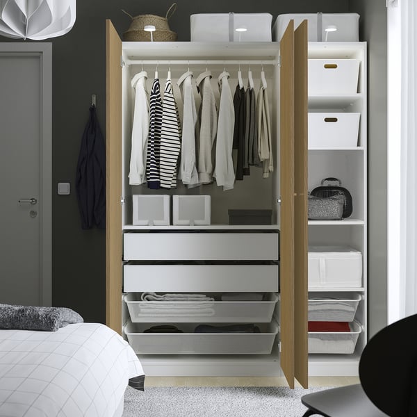 Open wardrobe with hangers, drawers, and shelves. Clothes hang, folded items in drawers, and bins on top shelf.