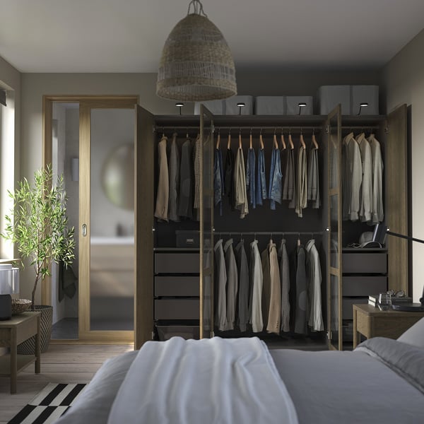 Modern bedroom with PAX wardrobe, hanging clothes, drawers, and open door.
