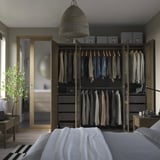 Modern bedroom with PAX wardrobe, hanging clothes, drawers, and open door.