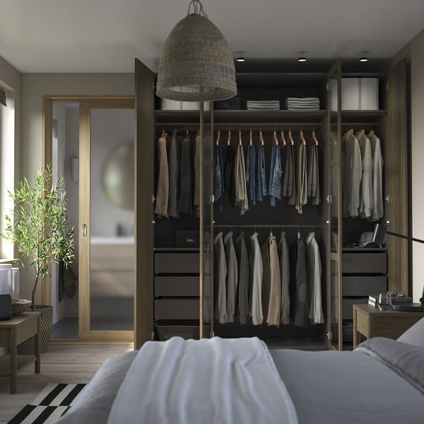 Modern bedroom with a large PAX wardrobe, featuring hanging clothes, shelves, and drawers, with a pendant light above it.
