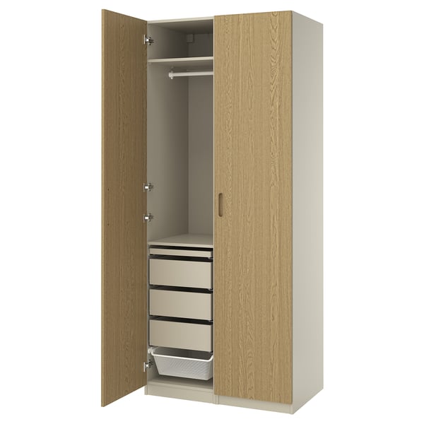 An open wooden PAX wardrobe with drawers and a hanging rod, featuring a light oak finish and a minimalist design.