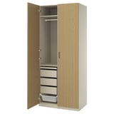 An open wooden PAX wardrobe with drawers and a hanging rod, featuring a light oak finish and a minimalist design.