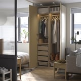 An open wooden PAX wardrobe. It hanging clothes, drawers, and storage boxes. A light illuminates the interior.