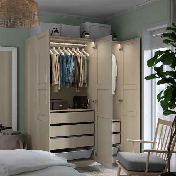 Bedroom with beige PAX wardrobe, clothes hangers visible, drawers with organizer mesh, soft-closing hinges, and built-in lights.