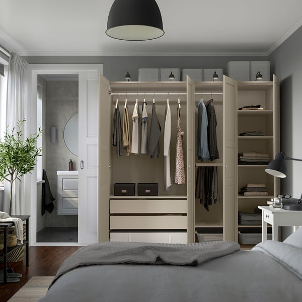 Modern bedroom with built-in wardrobe, clothes hangers, shelves, and drawers for organized storage. Grey-beige color scheme.