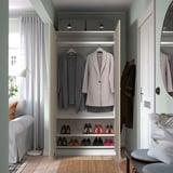 Open closet displaying clothes and shoes. White frame, gray interior, hangers with coats, shelves with shoes.