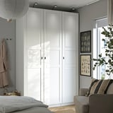 A white PAX wardrobe set, corner-spanning with soft-close doors and drawers, complementing a minimalist room.