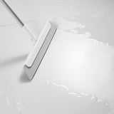 White squeegee with aluminum handle on clean floor, removing water and dirt.