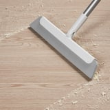 Floor squeegee with aluminum handle removes dirt and hair from floors.