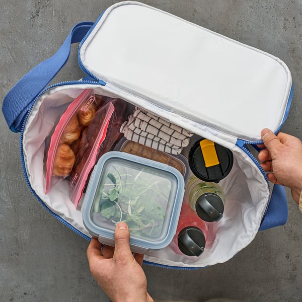 Open insulated PILLERSTARR bag revealing food and drinks kept cool, carried with shoulder strap.