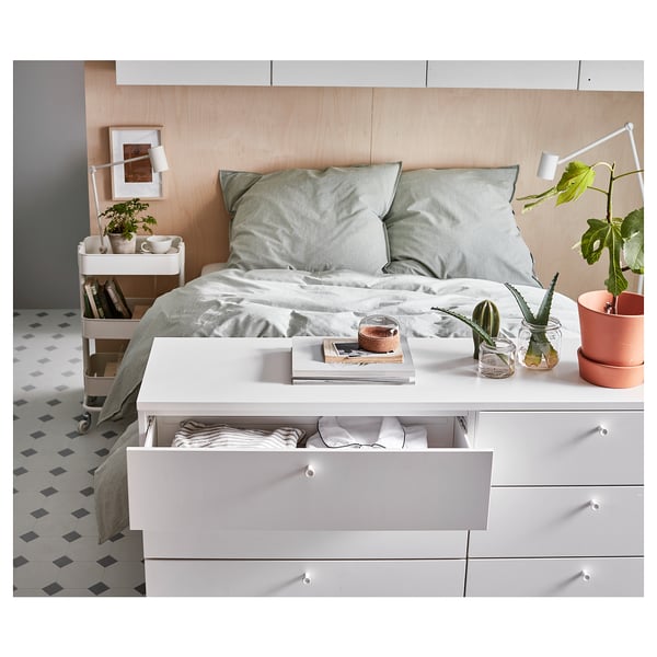 Modern bedroom with white PLATSA bed, gray linens, and storage drawers.