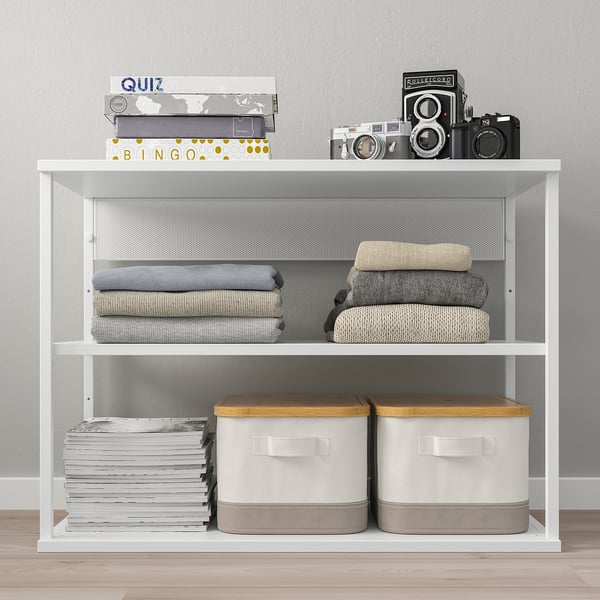 White PLATSA shelving unit with games, blankets, and storage boxes. Efficiently stores and displays various items.
