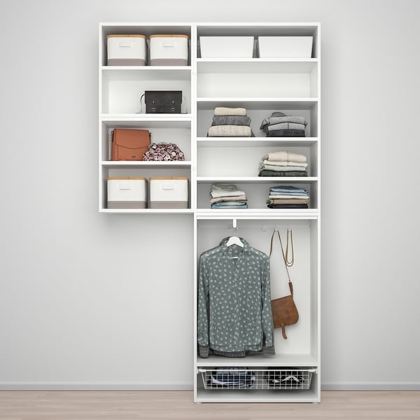 A white PLATSA wardrobe with shelves holding clothes and storage bins, featuring hanging garments and adjustable feet.