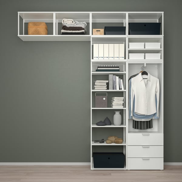 White PLATSA storage unit with shelves, hanging garments, and drawers against teal wall.