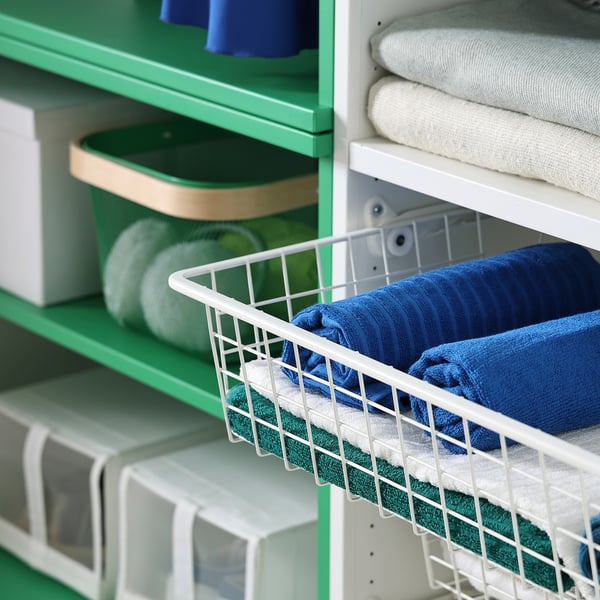 Folded towels organized in green PLATSA shelves, with wire baskets holding blue and green towels, mounted on white frames.