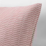 Close-up of rouge and white woven cushion cover, showing intricate striped pattern and quality cotton texture.