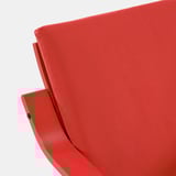 Bright red, modern upholstered armchair with smooth, curved back and sides, clean lines, and inviting texture.
