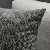 Close-up of soft, textured fabric pillow on a gray cushion, showcasing intricate weave and subtle shine.