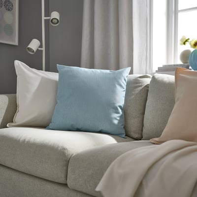 Domand, light grey-blue cushion, textured, on large sofa, with larger pillows & throw blankets
