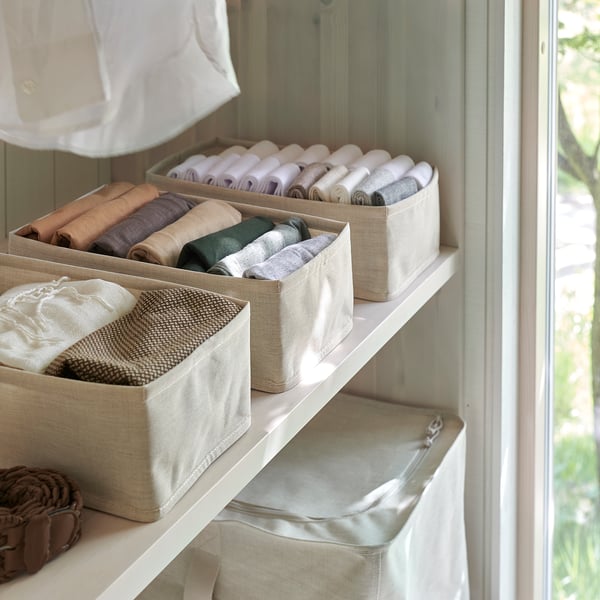 Organized shelves with folded clothes in fabric boxes, keeping items neat and accessible.