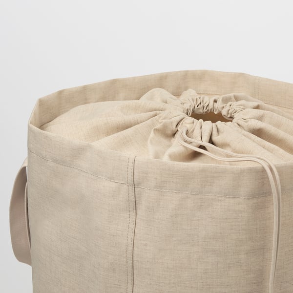 Cylindrical beige fabric laundry tote with drawstring closure. Handles on either side for carrying. Seamless design, ready for laundry duties.